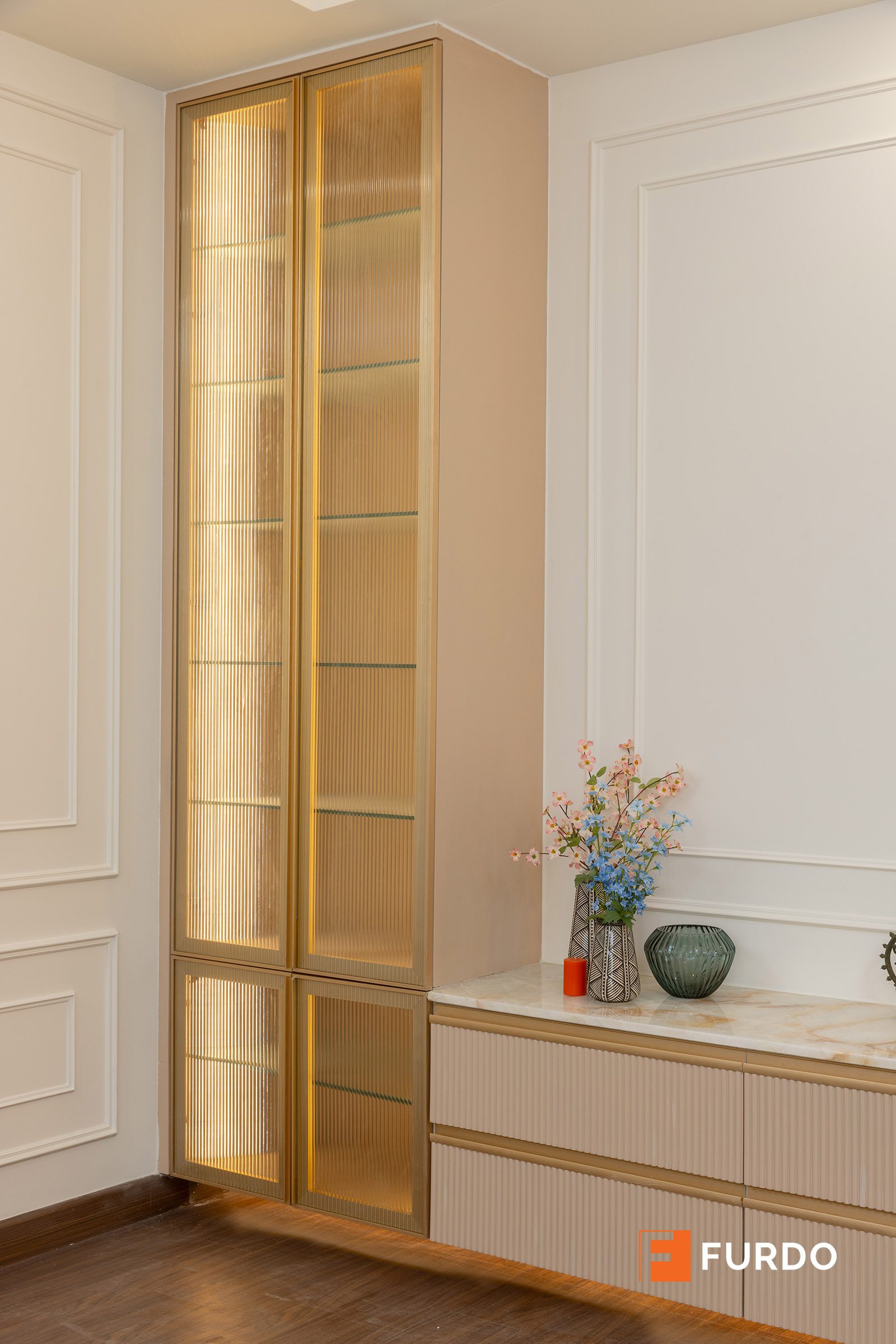 Luxury display and crockery storage design Hyderabad — a tall glass-fronted display unit with a lower drawer bank at Auro Kohinoor