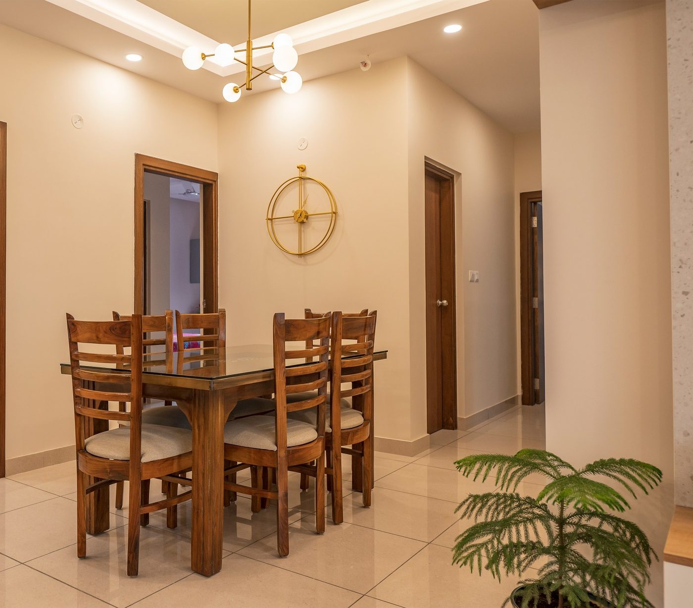 Dining space at Prestige Song of the South, Bangalore, with a wooden dining table, six chairs and a wall clock