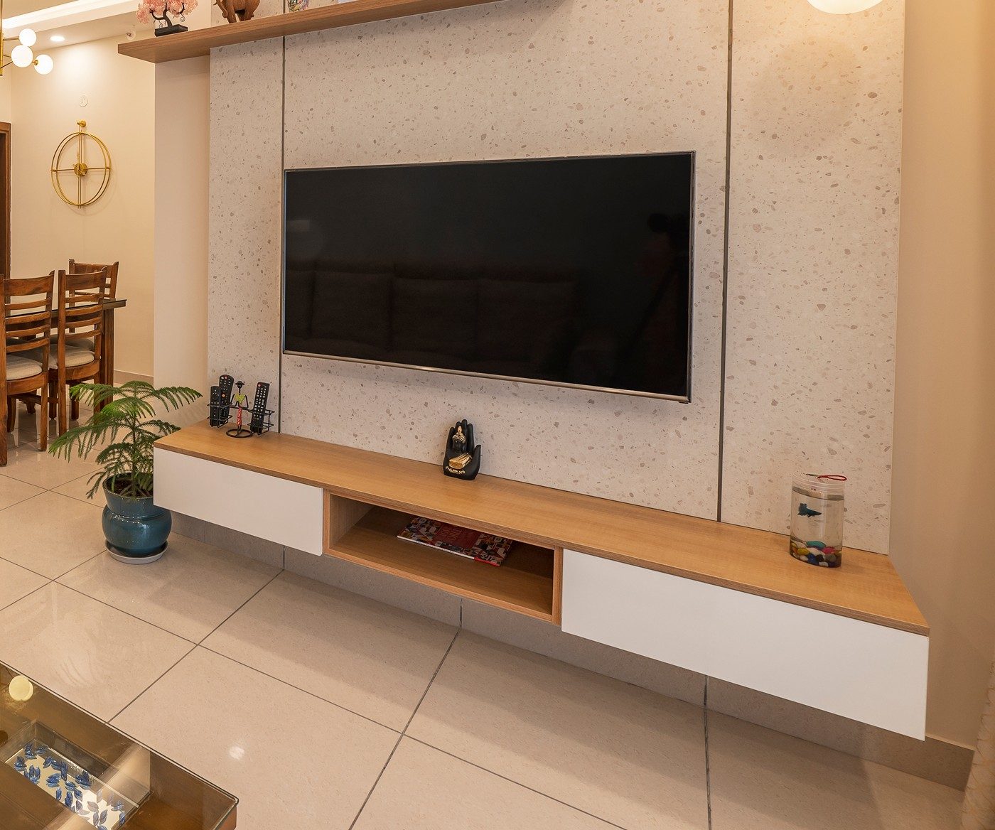 A textured stone feature wall behind a wall-mounted television, with a floating wood console below it