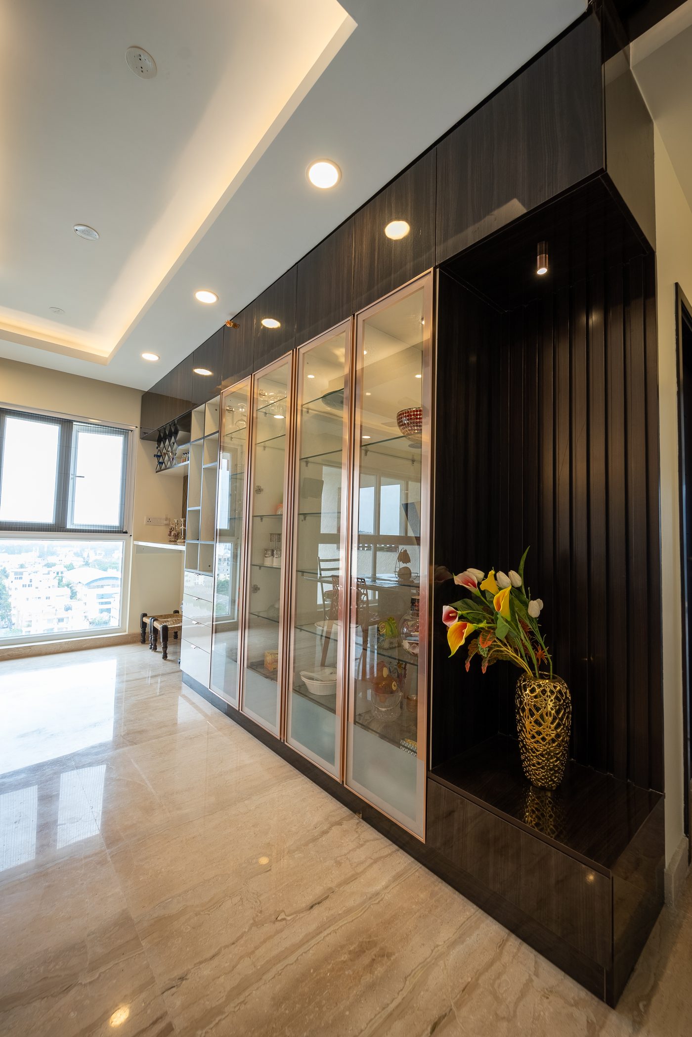Slim dark-framed glass partition separating a passage from the kitchen, closing off cooking noise and smell while keeping the daylight, in a completed home at Mahindra Windchimes, Bangalore