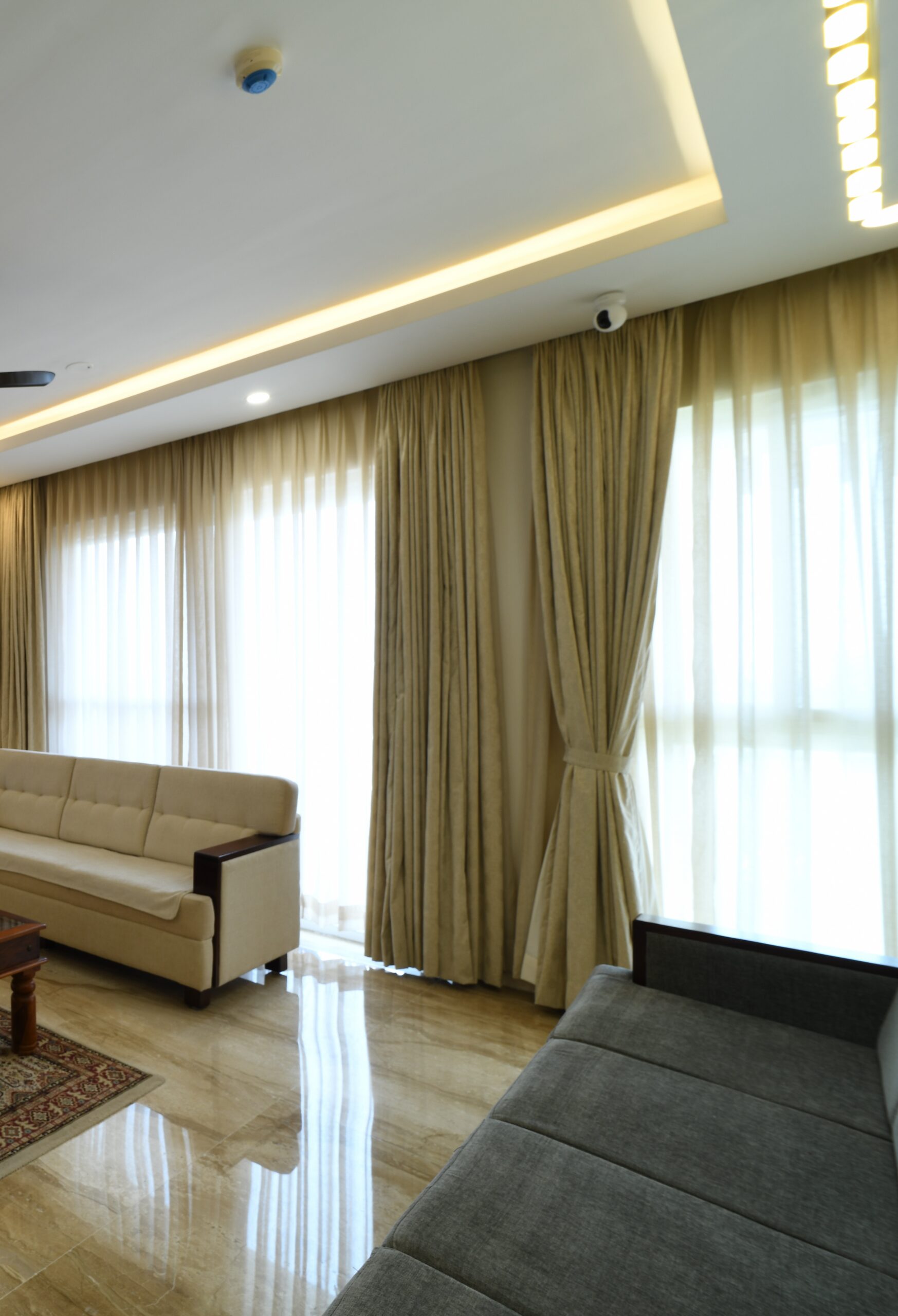 A living room seating area with layered curtains in a Bangalore home designed by Furdo
